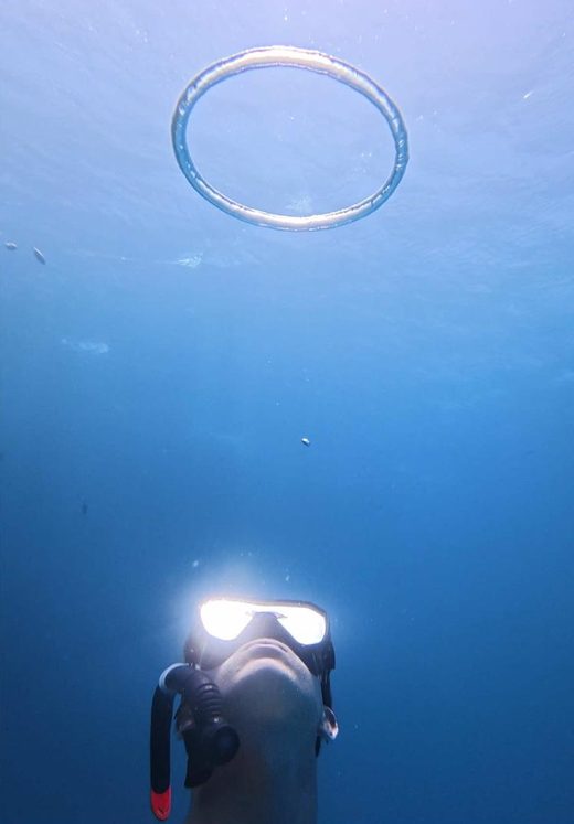 George looking up at a perfect bubble ring in open blue water